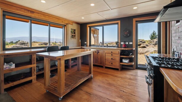 Una cocina moderna con armarios de madera, una isla grande y vistas a un paisaje rocoso.