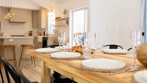 Un comedor con una mesa de madera dispuesta para una comida, incluyendo platos, vasos y cubiertos.
