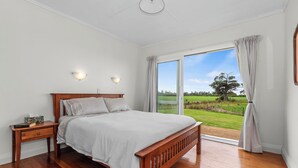 Un dormitorio con una cama de madera, una mesita de noche y un ventanal con cortinas.
