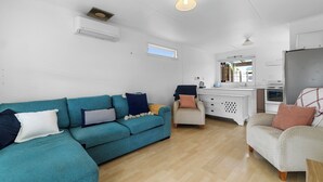 Una sala de estar con un sofá azul verdoso, un sillón color beige y un armario blanco.