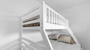 Una cama litera con estructura blanca y ropa de cama a rayas.