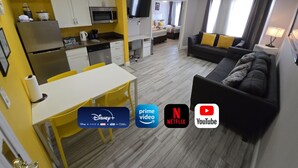 Un espacio habitable compacto con kitchenette, comedor y un sofá en la sala.