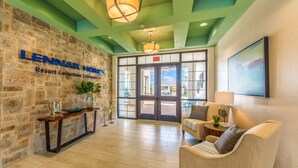 A lobby with a stone wall, a reception desk, a sofa, and a large window. - Home 9 Bed Pool Best Location Storey Lake (Kissimmee)