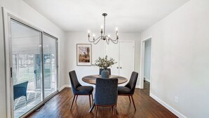 A dining area with a round table, four chairs, a chandelier, and a framed picture on the wall. - Modern, Fully Furnished Retreat, Close to OSU Campus, Downtown and Riverside Hos (Columbus)
