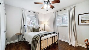 A bedroom with a bed, a standing lamp, a ceiling fan, and two windows with curtains. - Modern, Fully Furnished Retreat, Close to OSU Campus, Downtown and Riverside Hos (Columbus)
