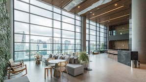 A spacious lounge area with large windows, a seating area with sofas and chairs, and a bar counter. - AV.NU by Viva - Residencial Alto Padrão próximo a Business Center na Nações Unidas. (São Paulo)