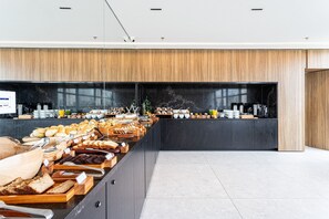 Een moderne keuken met een lange toonbank waarop diverse gebakjes en ontbijtartikelen staan.