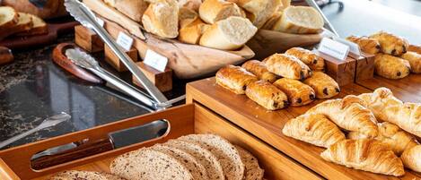 Un bufé de desayuno con panes y bollería variada.