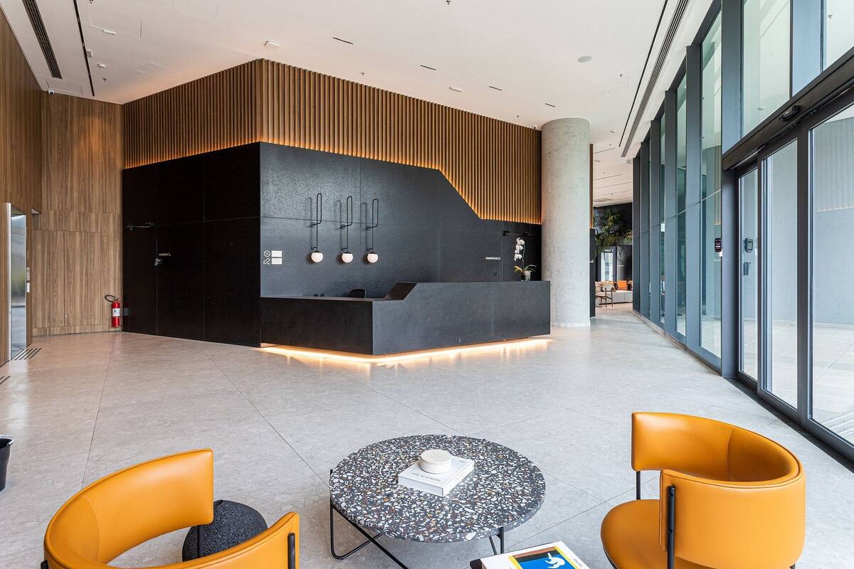 Een moderne lobby met een receptiebalie, zithoek en grote ramen.