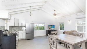 A spacious kitchen with white cabinetry, a large island, and a dining area with a wooden table and chairs. - Bright & Roomie Bottle Creek Apts (Bottle Creek)