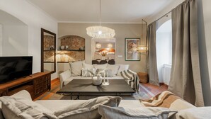 Een moderne woonkamer met een flatscreen televisie, een bank, een salontafel en een kroonluchter.