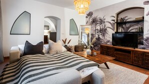 Een moderne slaapkamer met een groot bed, een televisie en een decoratieve spiegel.