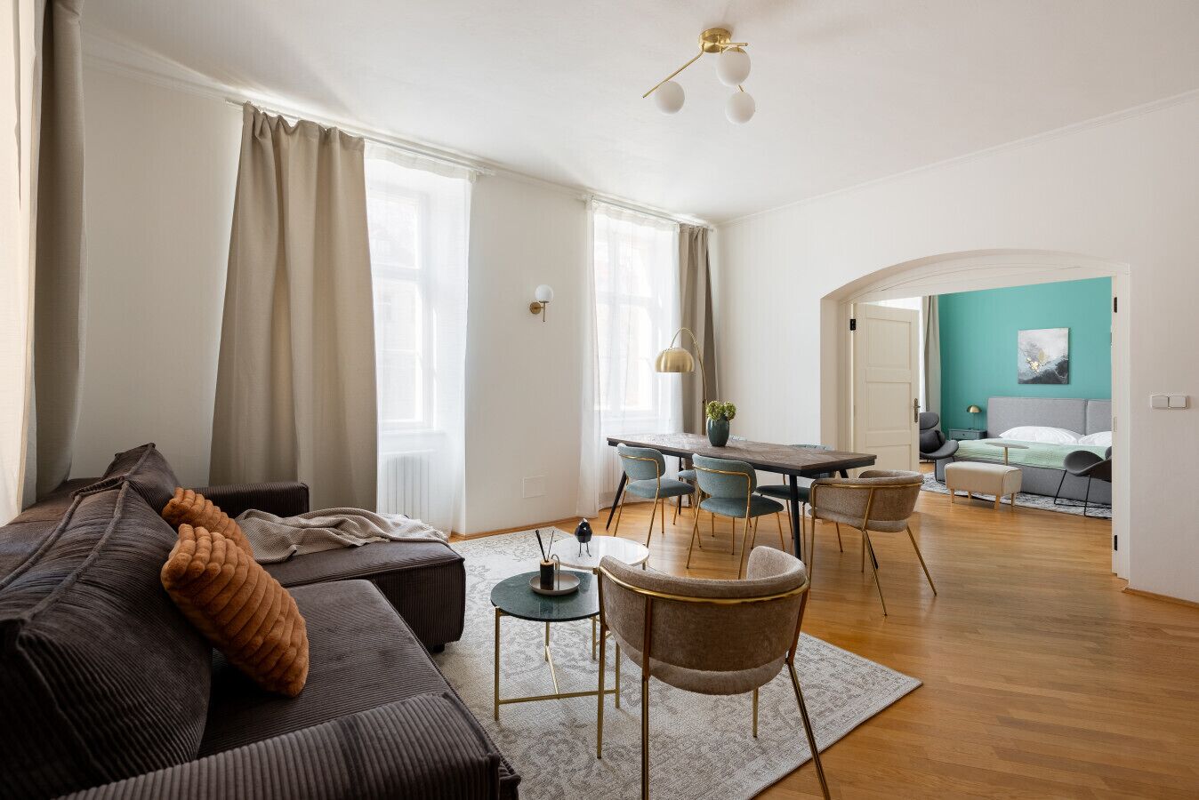 Ein geräumiger Wohnbereich mit Sofa, Stühlen, einem Esstisch und einer Küche im Hintergrund.