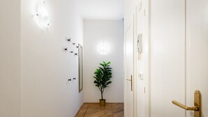 Een hal met witte wanden, een houten vloer, een kamerplant en een deur met een gouden handvat.