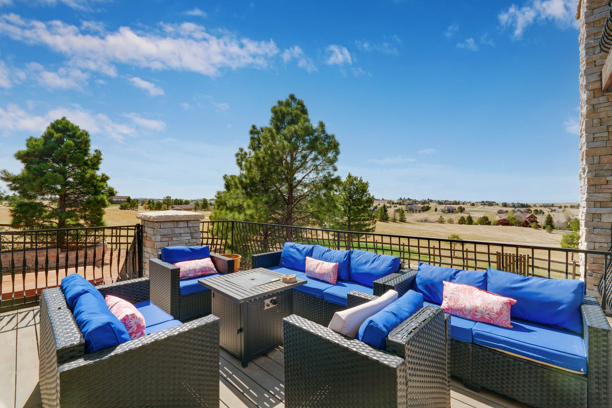 Eine Terrasse im Freien mit Korbmöbeln und blauen Kissen, mit Blick auf eine malerische Landschaft.