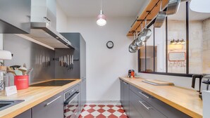 A modern kitchen with stainless steel appliances, a wooden countertop, and a red and white checkered floor.