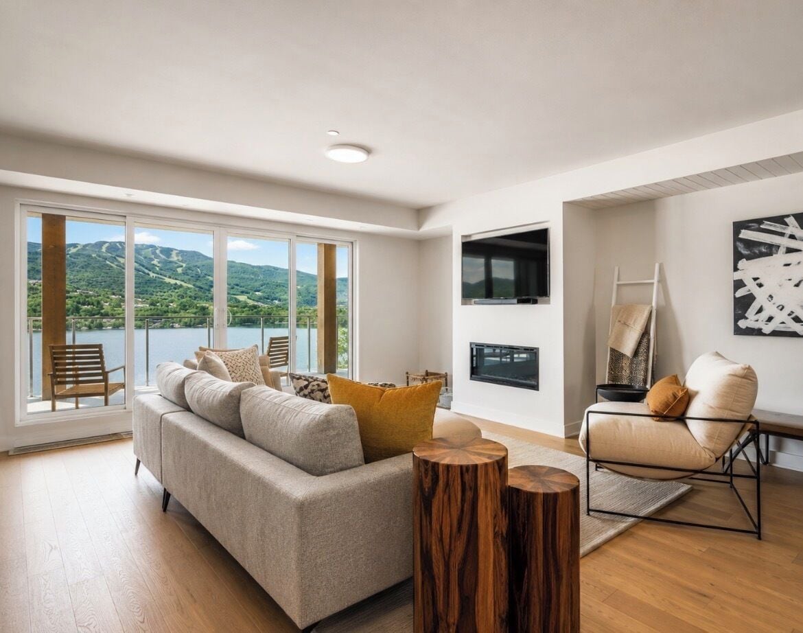 Una sala moderna con sofá, sillón y mesitas de madera.