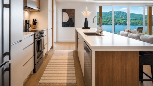 Una cocina moderna con una isla central, electrodomésticos de acero inoxidable y vistas a un lago.