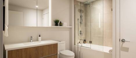 A modern bathroom with a wooden vanity, a glass shower enclosure, and a white toilet.