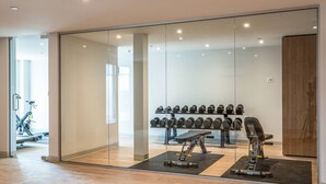 Un gimnasio moderno con equipamiento de ejercicio, una pared de mancuernas y una cinta de correr.