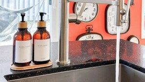 Eine Küche mit einem außergewöhnlichen Wasserhahn, zwei Seifenspender und einer Wanduhr.