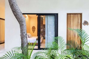 A modern room with a bed, a sliding glass door, and a wooden door.