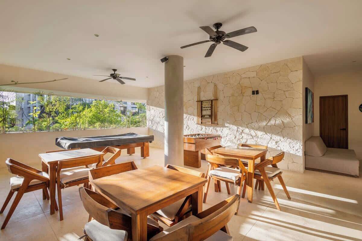 A spacious room with wooden furniture, a stone wall, and a ceiling fan.