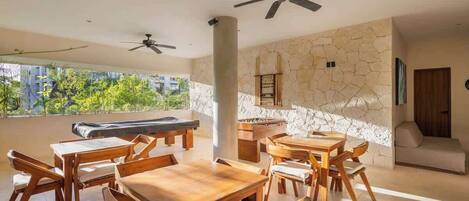 A spacious room with wooden furniture, a stone wall, and a ceiling fan.