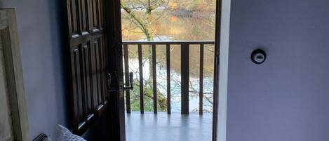 A bedroom with a bed, a window, and a door leading to a balcony.