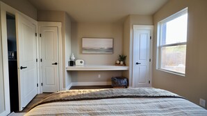 A bedroom with a bed, a desk with a chair, a window, and two doors. - Charming cabin with full RV resort access incl, WiFi in welcoming South Weber (South Weber)