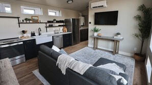 A modern kitchen with built-in appliances, a dining area with a table and chairs, and a living room with a sofa and a TV. - Charming cabin with full RV resort access incl, WiFi in welcoming South Weber (South Weber)