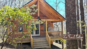 Eine Holzhütte mit Veranda, umgeben von Bäumen.