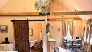 A bedroom with a large bed, a chair, a desk, and a chandelier.
