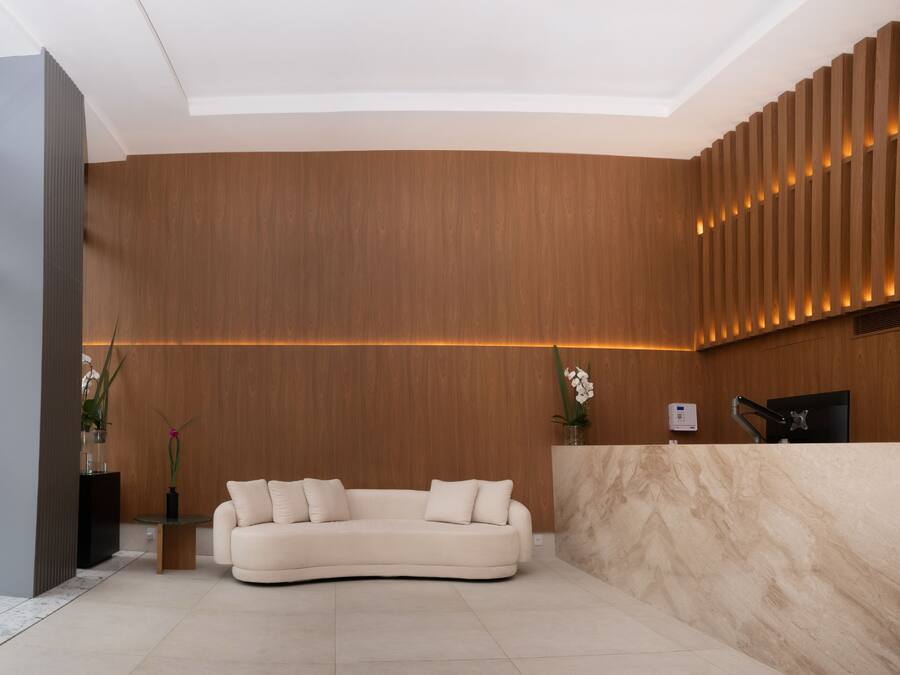 A modern reception area with a curved sofa, wooden paneling, and a marble reception desk.