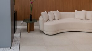 Una sala de estar moderna con un sofá curvo, una mesita redonda y una planta en maceta.