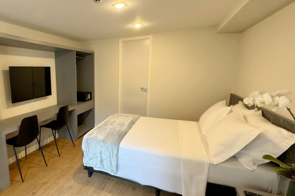 Ein Hotelzimmer mit Bett, Schreibtisch mit Stuhl, Fernseher und Tür.