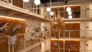 Un interior de varios niveles con lámparas esféricas colgantes, plantas en macetas y diseños de pared con motivos.