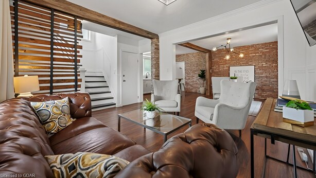 Een moderne woonkamer met een leren bank, een glazen salontafel en een accentmuur van baksteen.