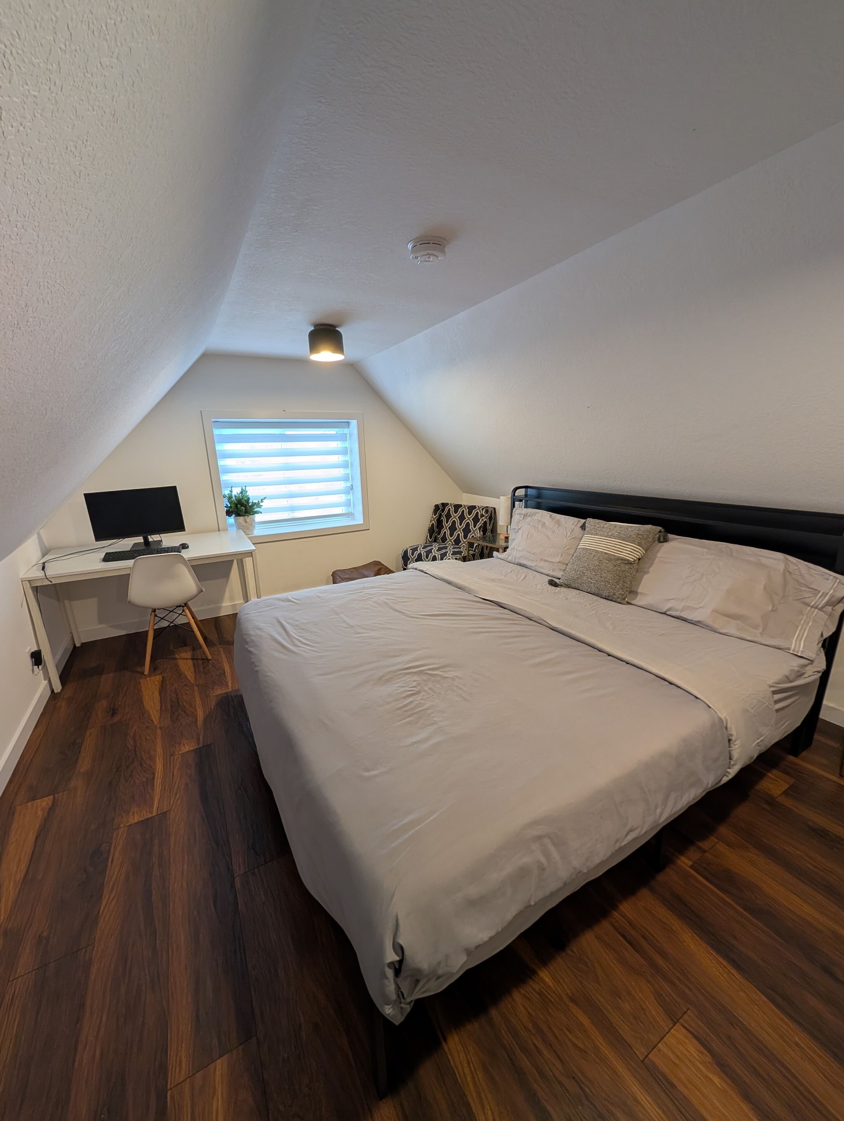 A bedroom with a bed, a desk, and a computer.