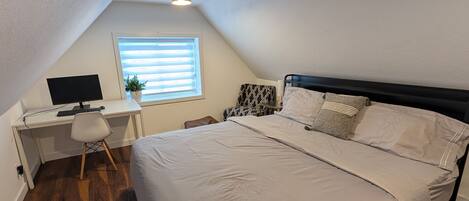 A bedroom with a bed, a desk, and a computer.