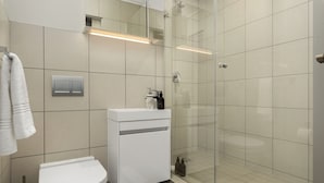 A modern bathroom with a toilet, sink, and glass-enclosed shower. - Foreshore Place | Modern Studio | Netflix (Cape Town)