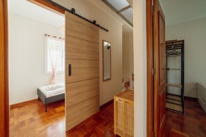 Een slaapkamer met een bed, een houten garderobe, een spiegel en een houten vloer.