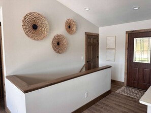 A reception area with a wooden reception desk, three woven wall decorations, a wooden door, and a window with a view.