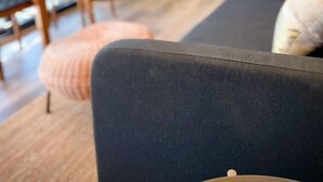 A modern interior with a sofa, ottoman, and a dining area. - Outscape Lago Chapo (Puerto Montt)