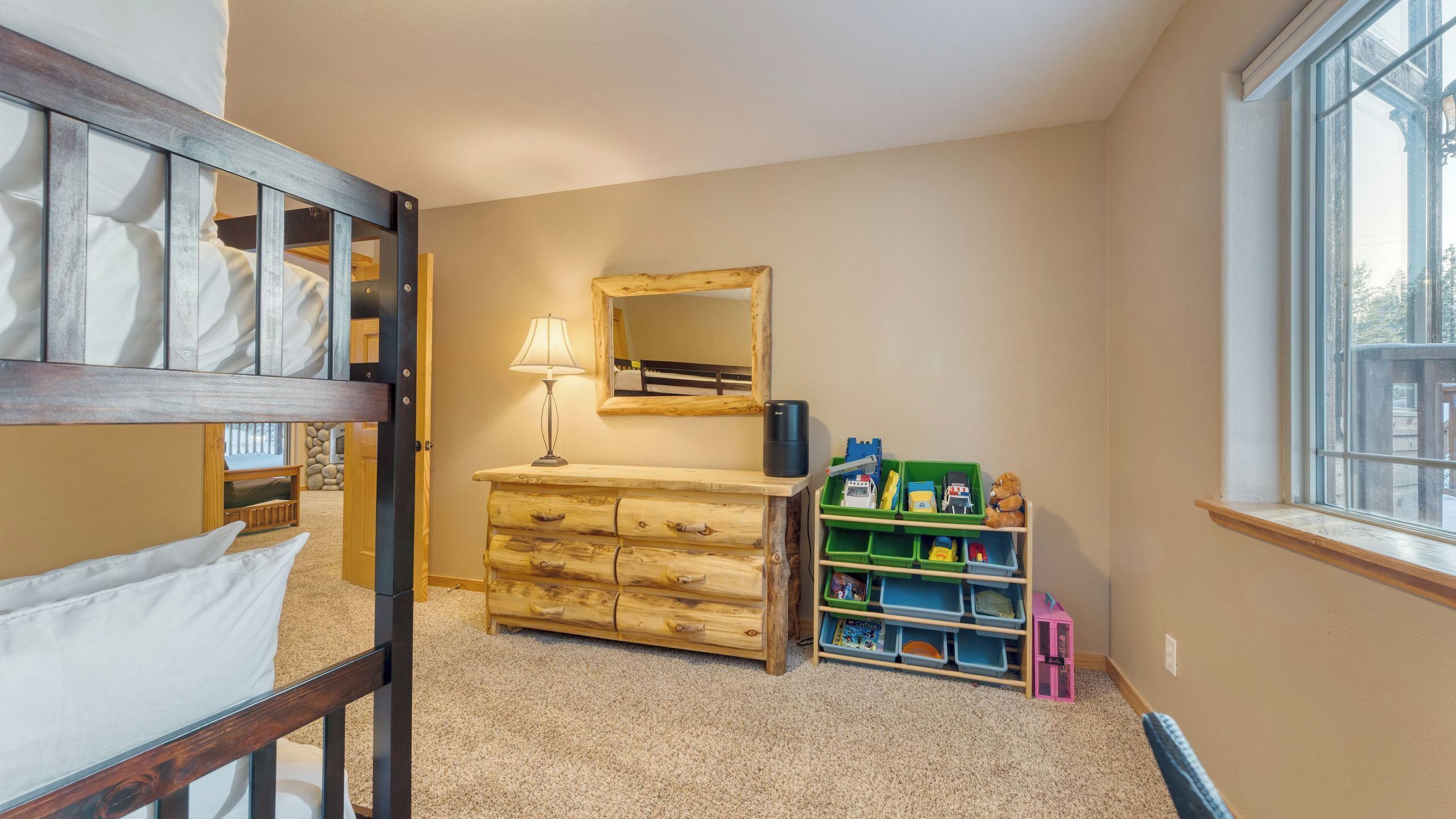 A child's room with bunk beds, a dresser, a mirror, and a window.