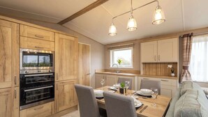 A modern kitchen with wooden cabinets, a built-in oven, and a dining area with a table set for four.