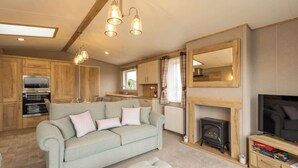 A cozy living room with a sofa, fireplace, television, and kitchen area with wooden cabinets and appliances.