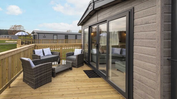 A covered outdoor area with wicker furniture and a wooden deck.