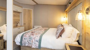 A bedroom with a bed, bedside table, lamp, and a mirror.