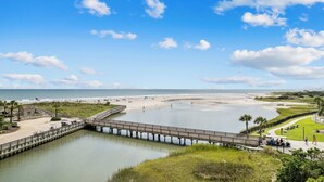 A coastal view with a bridge over water, beach, and a grassy area with a fence. - Family-Friendly 2BR Condo Near Beach & Barefoot Landing (Myrtle Beach)
